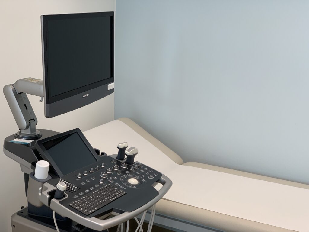 Ein Ultraschallgerät vor eine Patient:innenliege in der Ordination von OA Dr. Miloš Tajsić